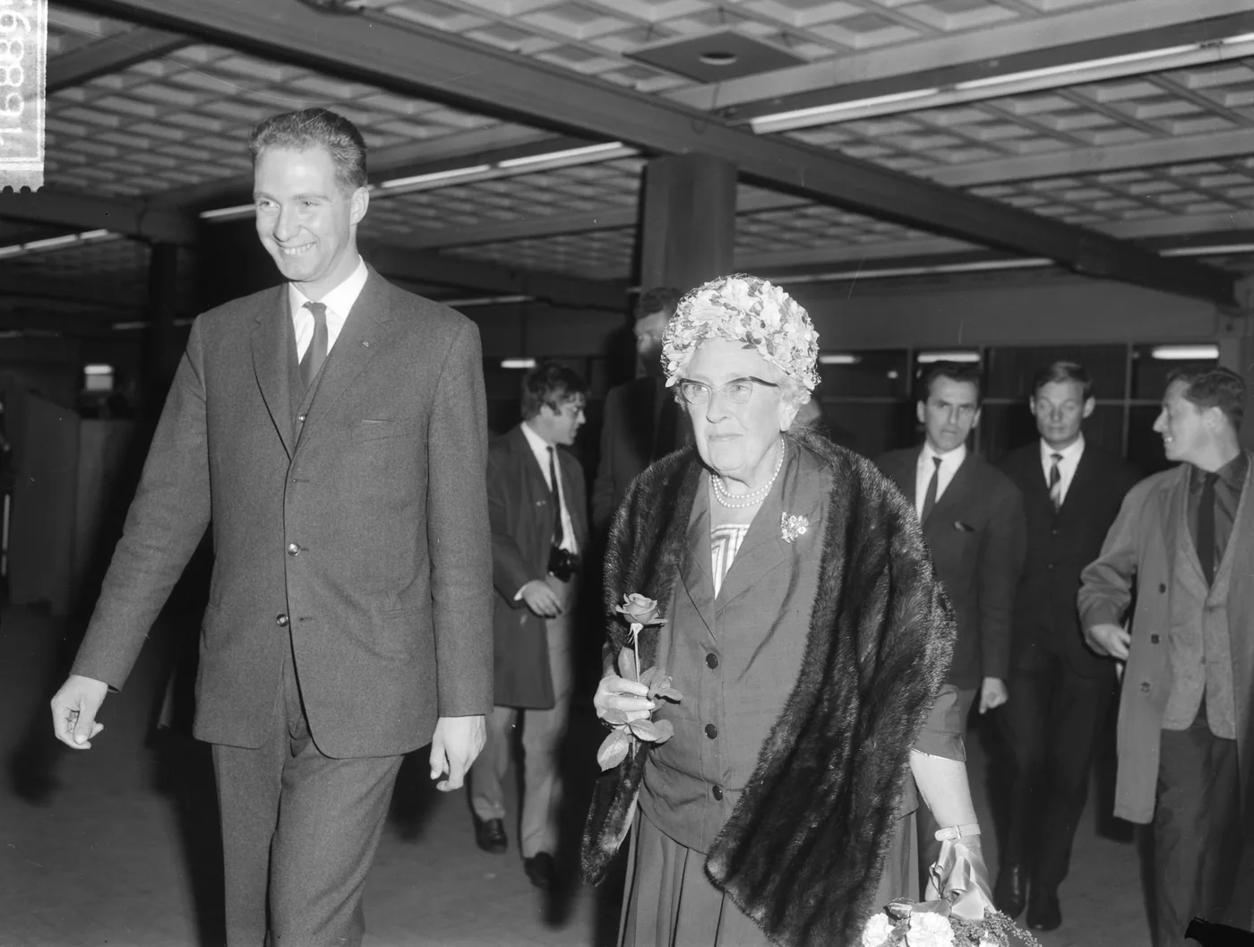 Agatha Christie arriving at Schiphol airport in 1964, surrounded by press photographers