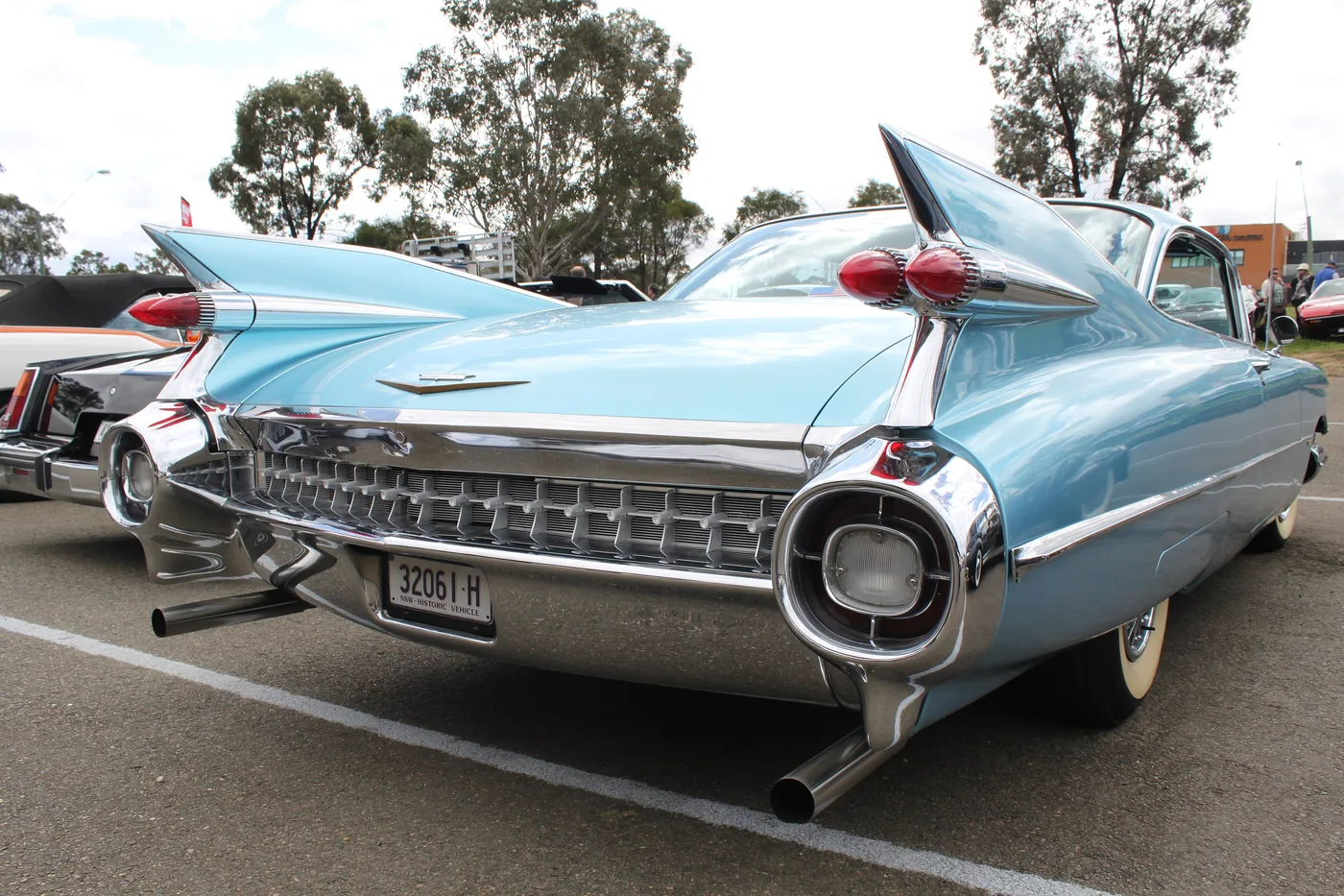 The tailfins and twin bullet tail lights of a light blue 1959 Cadillac Eldorado at a car show
