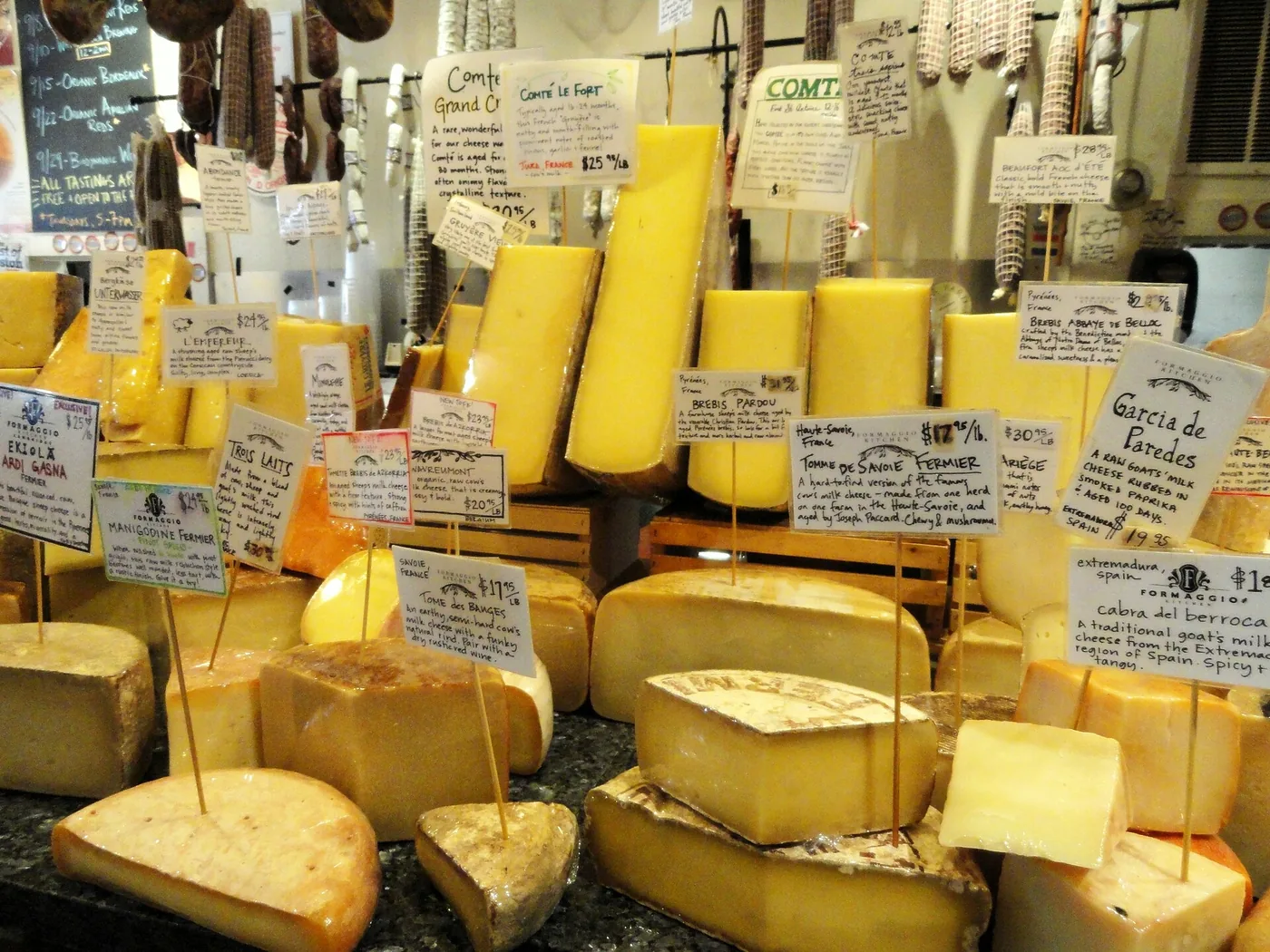 A cheese counter in a Cambridge, Massachusetts grocery store, wheels and wedges under handwritten labels