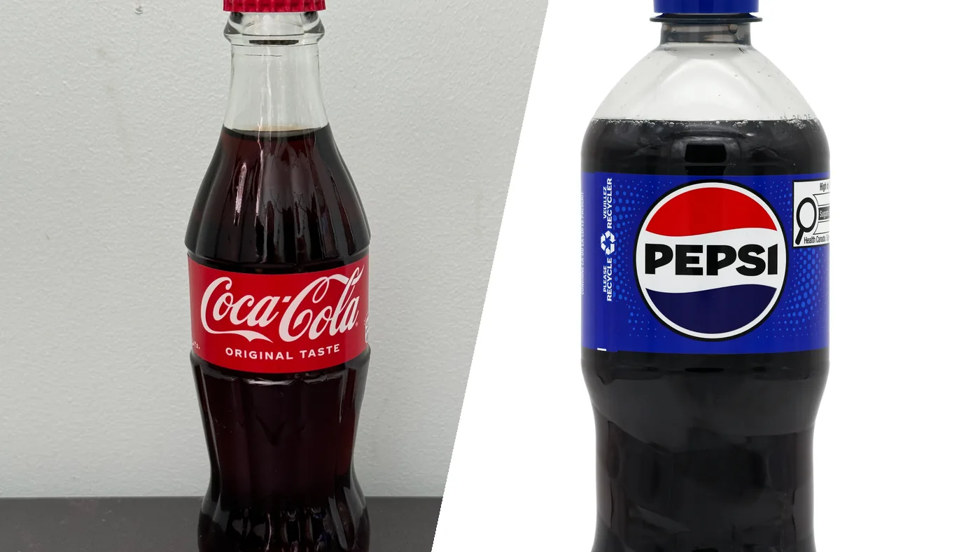A Coca-Cola glass bottle and a Pepsi bottle side by side