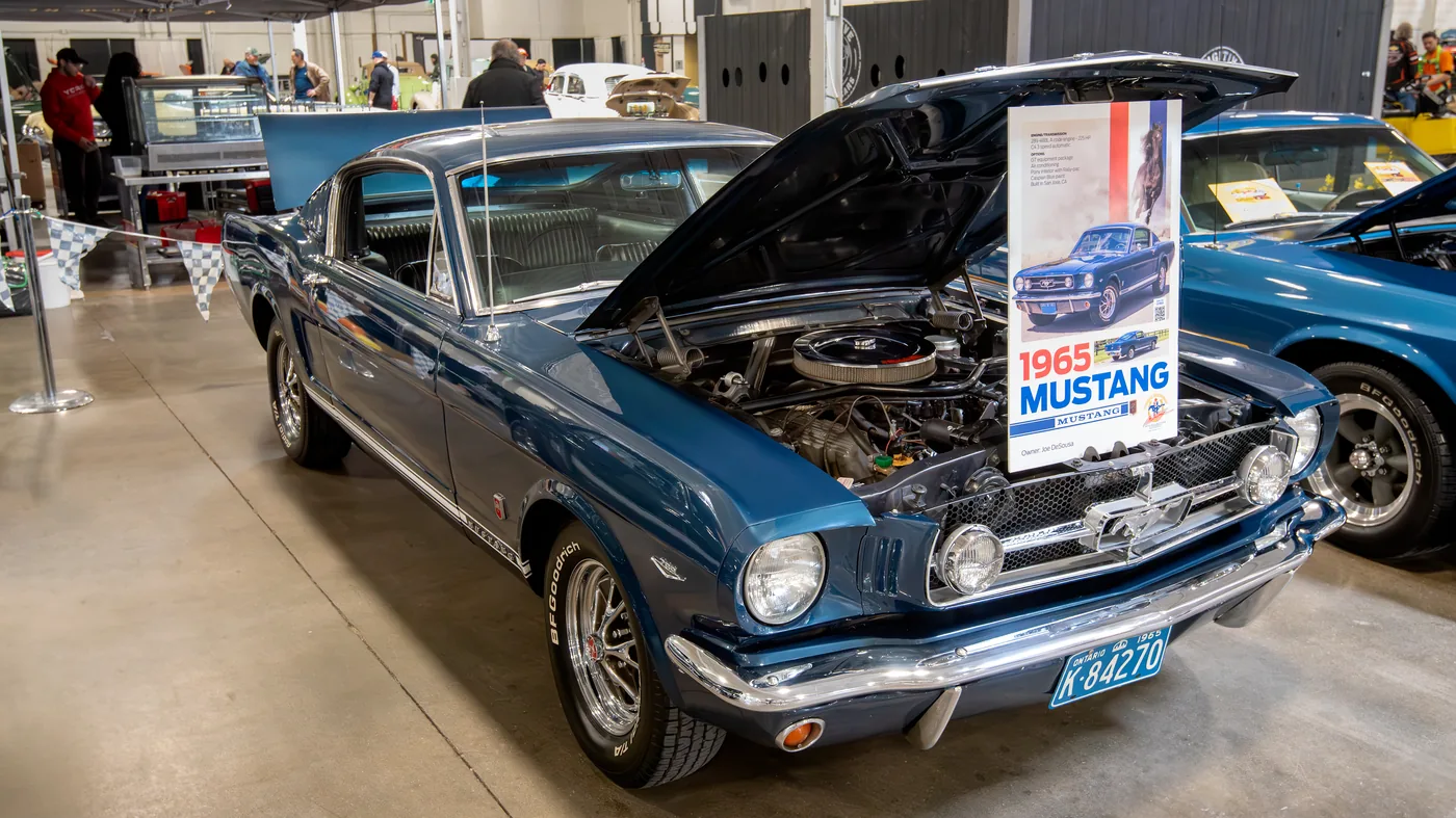 A 1965 Ford Mustang GT fastback in dark green, photographed at a car show