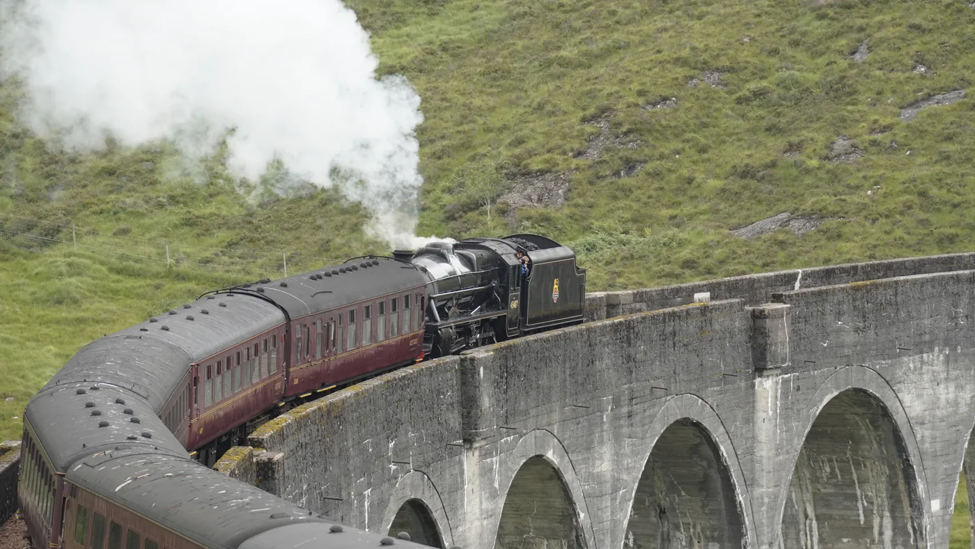 A steam train dressed as the Hogwarts Express crossing the Glenfinnan Viaduct in Scotland