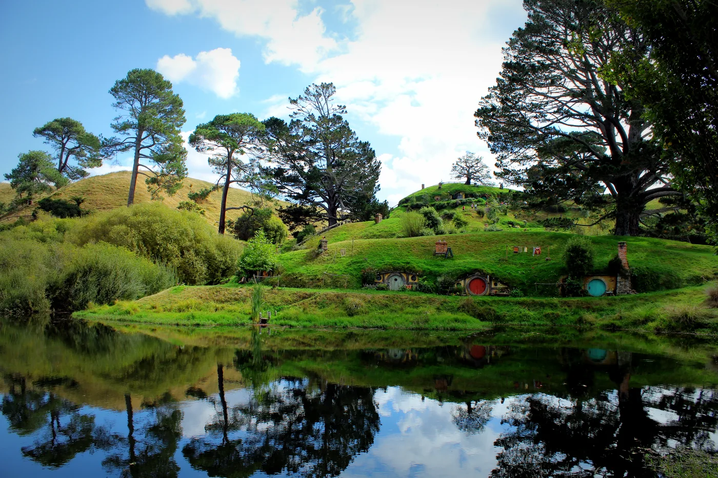 Hobbit holes reflected in the water at the Hobbiton movie set, Matamata, New Zealand