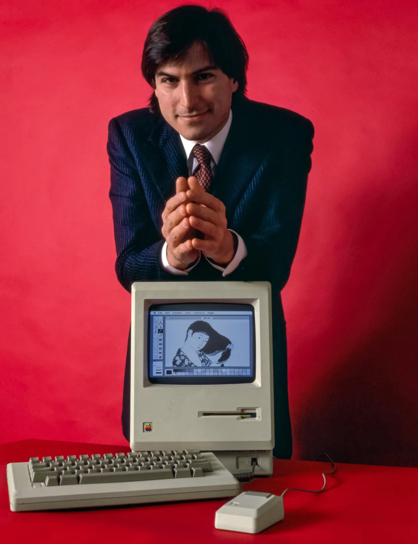 Steve Jobs leaning over the original Apple Macintosh, January 1984