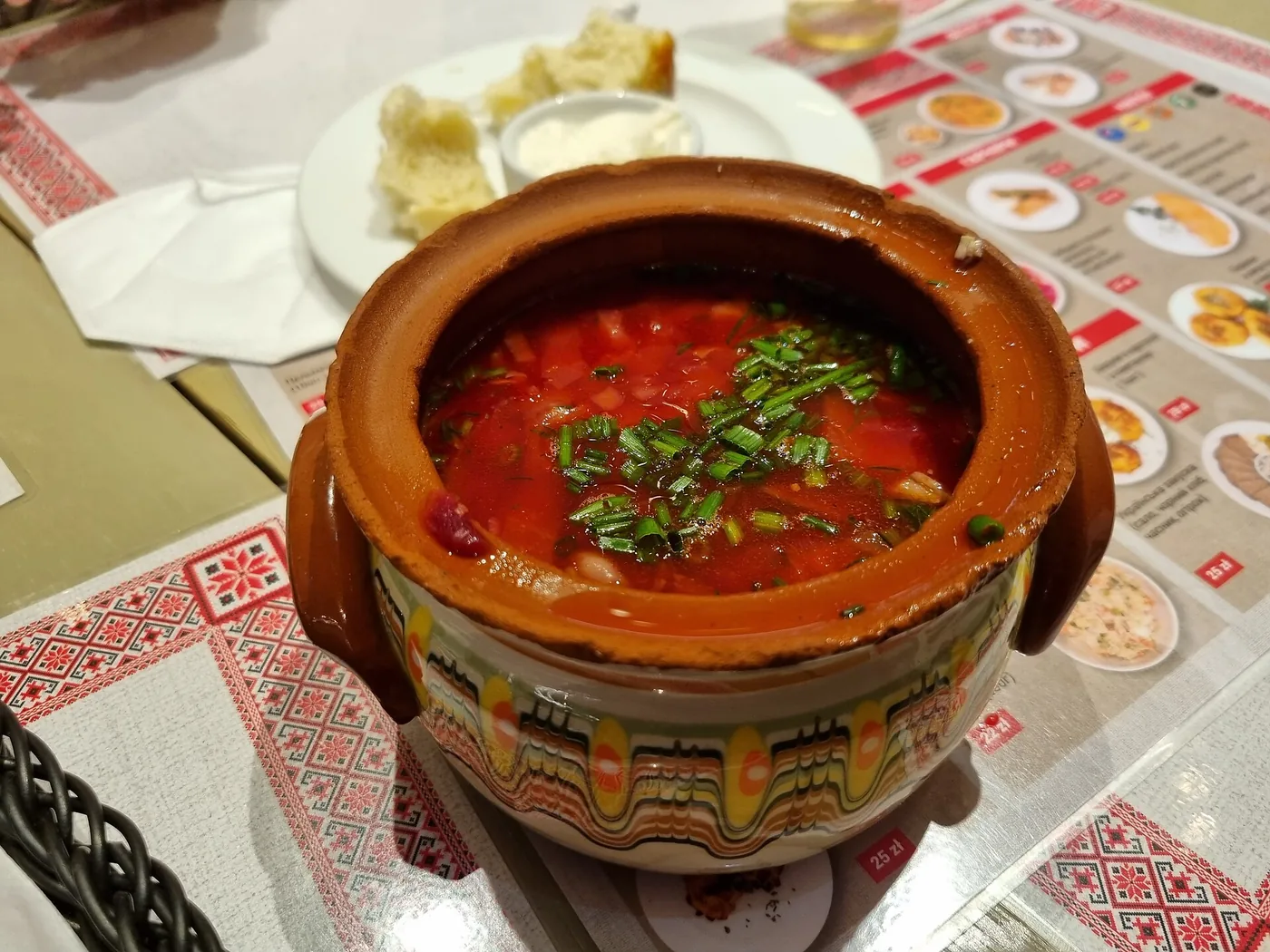 Ukrainian borscht in a clay pot on an embroidered tablecloth